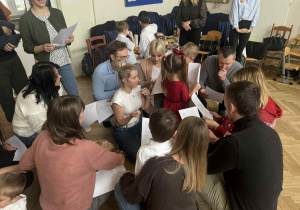 Zdjęcie przedstawia rodziców z tekstami w ręku, przygotowujących się do występu.