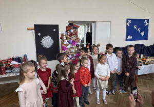 Zdjęcie przedstawia dzieci stojące przy mężczyźnie, przebranym za choinkę.