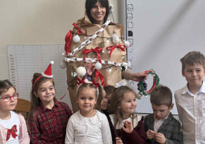 Zdjęcie przedstawia dzieci stojące obok kobiety przebranej za choinkę.