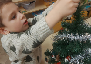 chłopiec ubierający choinkę