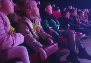 Zdjęcie przedstawia dzieci siedzące na widowni.