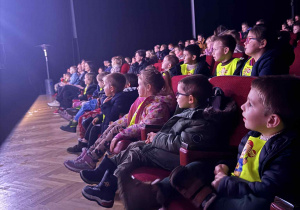 Zdjęcie przedstawia dzieci siedzące na widowni.