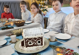 Dzieci siedzą za wspólnym stołem i jedzą potrawy Wigilijne
