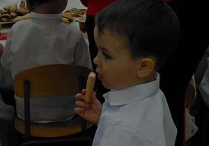 Na zdjęciu widzimy chłopca, który zjada ciastko.