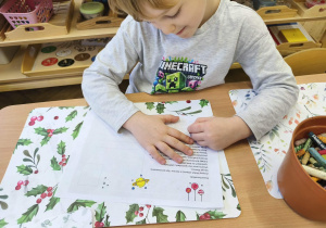 Zdjęcie przedstawia chłopca kolorującego kartkę