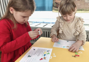 Zdjęcie przedstawia dwie dziewczynki ozdabiające kartki