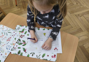 Zdjęcie przedstawia dziewczynkę piszącą na kartce