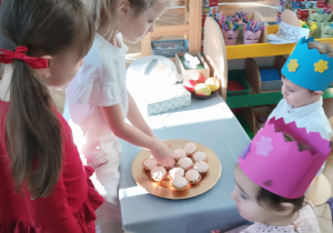 Dziewczynki się czestują babeczkami.