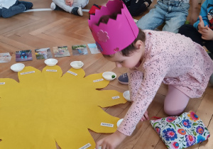 Dziewczynka układa koraliki w odpowiednie pojemniczki.