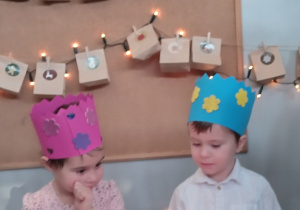 Dzieci siedzą na krzesłach i zdmuchują świeczki na urodzinowym torcie.