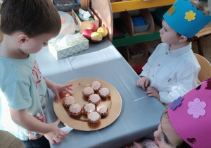 Chłopiec częstuje się babeczką.