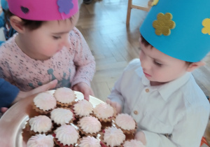 Dzieci stoją i trzymają babeczki.