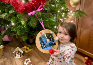 Na zdjęciu widzimy dziewczynkę, która wykonała bombkę dla sowjego brata.