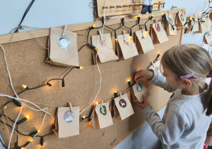 Na zdjęciu widzimy dziewczynkę, która odszukuje torebki z kolejnym zadaniem na weekend z kalendarza adwentowego.