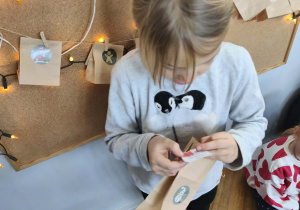 Na zdjęciu widzimy dziewcyznkę, która próbuje odczytać kolejne zadanie z kalendarza adwetnowego.