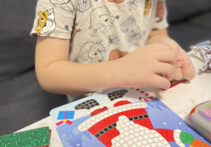 Na zdjęciu widzimy chłopca, który tworzy mozaikę dla bliskiej osoby.
