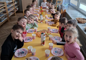 dzieci siedzą przy urodzinowym stole