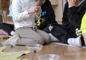 dziewczynka w koronie nawleka koraliki na sznurek