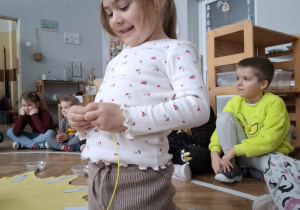 dziewczynka w koronie nawleka koraliki na sznurek