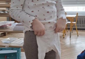 dziewczynka w koronie przykłada małe rajstopki do swoich nór