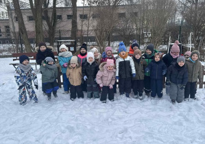 Zdjęcie przedstawia dzieci stojące na śniegu w zimowej scenerii.