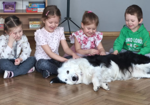 Pies leży koło siedzących dzieci