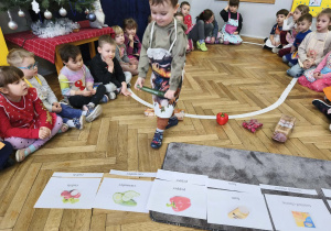 Na zdjęciu widzimy chłopca, który trzyma w ręku ogórka i przyporządkowuje go do ilustracji.