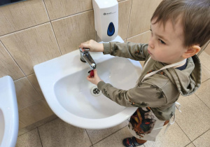 Na zdjęciu widzimy chłopca, który myje rzodkiewkę.