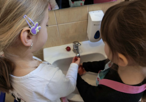 Na zdjęciu widzimy dziewczynki, które myją pomidora i rzodkiewkę.