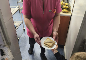 Na zdjęciu widzimy chłopca, który przekazuje talerz z tostem Pani Żanetce.