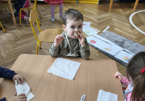 Na zdjęciu widzimy chłopca, który zjada tosta.