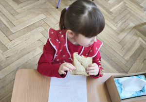 Na zdjęciu widzimy dziewczynkę, która zjada tosta.