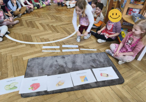 Na zdjęciu widzimy dziewczynkę, która przyporządkowuje nazwę w języku angielskim do ilustracji przedstawiającej dane produkty spożywcze.