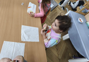 Na zdjęciu widzimy dziewczynkę, która zjada tosta.