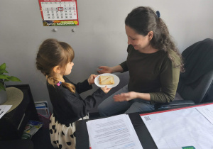 Na zdjęciu widzimy dziewczynkę, która częstuje Panią Ewę wykoananym tostem.