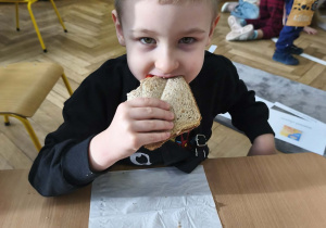 Na zdjęciu widzimy chłopca, który zjada tosta.