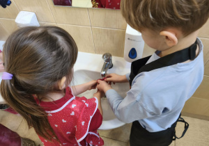 Na zdjęciu widzimy chłopca i dziewczynkę, którzy myją rzodkiewki.