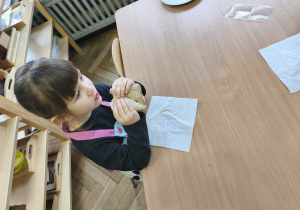 Na zdjęciu widzimy dziewczynkę, która zjada tosta.