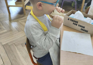 Na zdjęciu widzimy chłopca, który zjada tosta.