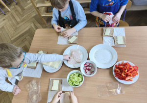 Na zdjęciu widzimy dzieci, które tworzą zdrowe tosty.