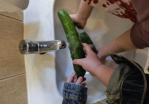 Na zdjęciu widzimy dziewczynki, które myją ogórki.