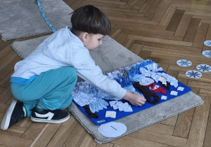 Na zdjęciu widzimy chłopca, który chowa smaczka w macie węchowej.