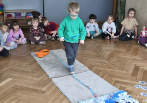 Na zdjęciu widzimy chłopca, który idzie noga za nogą po smyczy. W ręku trzyma łyżkę ze smaczkiem.