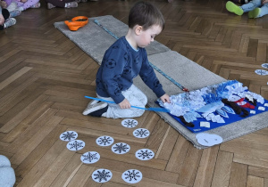 Na zdjęciu widzimy chłopca, który chowa smaczka w macie węchowej.