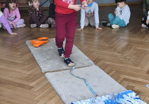 Na zdjęciu widzimy chłopca, który idzie noga za nogą po smyczy. W ręku trzyma łyżkę ze smaczkiem.