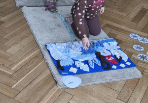 Na zdjęciu widzimy dziewczynkę, która chowa smaczka w macie węchowej.