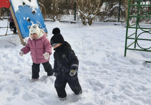 Na zdjęciu widzimy dziewczynkę i chłopca, którzy bawią się na śniegu.