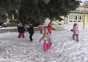 Na zdjęciu widzimy grupkę dzieci, które bawią się na śniegu.