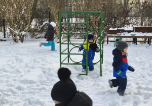 Na zdjęciu widzimy grupkę dzieci, które bawią się na śniegu.