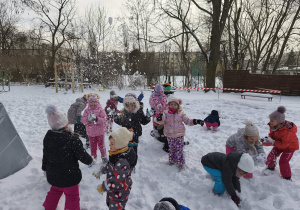 Na zdjęciu widzimy grupkę dzieci, które bawią się na śniegu.